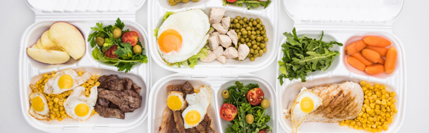 panoramisch shot van eco-pakketten met appels, groenten, vlees, gebakken eieren en salades op witte achtergrond  - Foto, afbeelding
