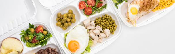 панорамний знімок екологічних пакетів з яблуками, овочами, м'ясом, смаженими яйцями та салатами на білому тлі
  - Фото, зображення
