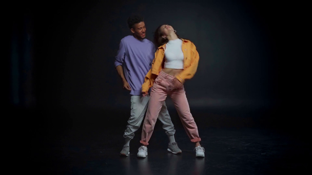 krullend Afrikaans amerikaanse man en stijlvolle vrouw dansen op zwart  - Video
