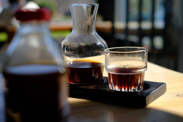 jug and glass of fresh cold brewed black coffee on cafe table - Fotó, kép