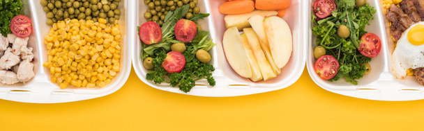 panoramic shot of eco packages with vegetables, apples, meat, fried egg and salads isolated on yellow     - Photo, Image