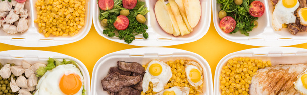 plano panorámico de paquetes ecológicos con verduras, manzanas, carne, huevos fritos y ensaladas aisladas en amarillo
     - Foto, imagen