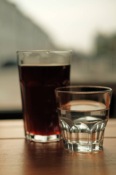 glasses of fresh cold brewed black coffee and clear water on cafe table - Fotografie, Obrázek