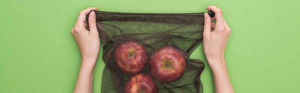 vue recadrée d'une femme tenant des pommes dans un sac écologique isolé sur une photo panoramique verte
 - Photo, image