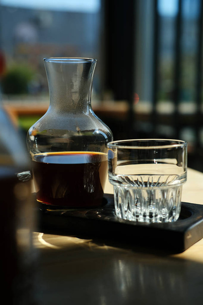 jug and glass of fresh cold brewed black coffee on cafe table - Foto, Imagem