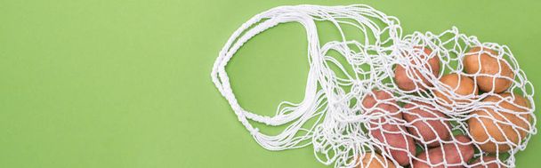 top view of ripe potato in string bag isolated on green - Photo, Image