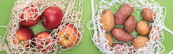top view of apples and potato in string bags isolated on green - 写真・画像