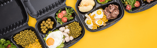 plano panorámico de paquetes ecológicos con manzanas, verduras, carne, huevos fritos y ensaladas aisladas en amarillo
     - Foto, Imagen