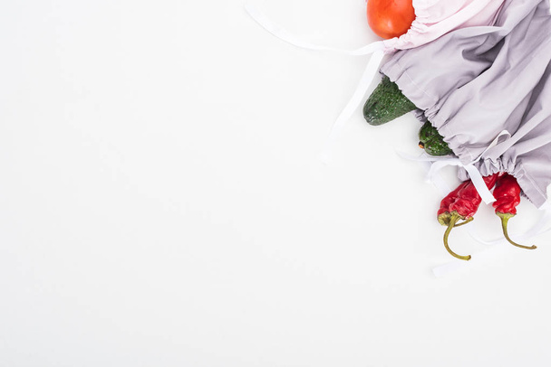 felülnézet az avokádó, a paradicsom és a chili paprika az öko-barát táskák elszigetelt fehér és másolási tér - Fotó, kép
