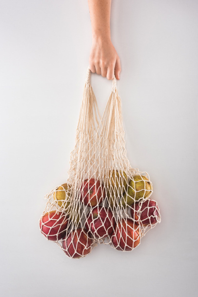 cropped view of woman holding eco friendly string bag with apples and pears isolated on white - Zdjęcie, obraz