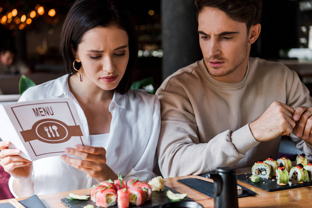handsome man sitting near attractive woman with menu in hands  - Photo, Image