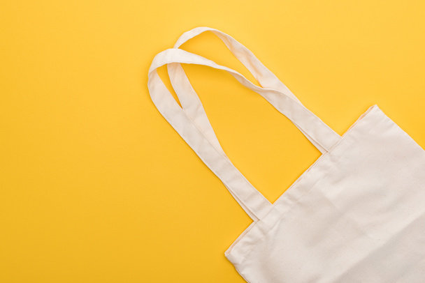 top view of cotton white eco friendly bag isolated on yellow - Foto, afbeelding