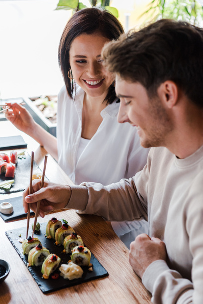 selective focus of young woman looking at man in sushi bar - 写真・画像
