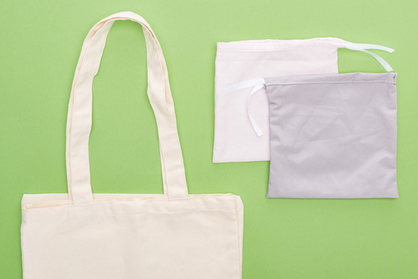 top view of empty cotton eco bags isolated on green - Foto, afbeelding
