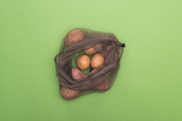 top view of fresh whole potatoes in eco friendly bag isolated on green - Photo, Image