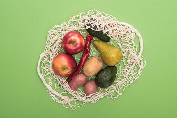 верхний вид овощей и фруктов в нитке мешок изолирован на зеленый
 - Фото, изображение