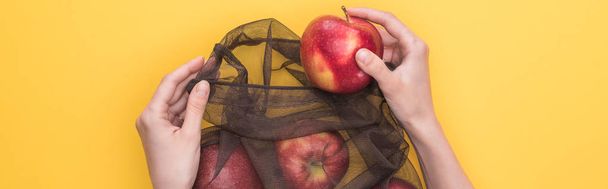 rajattu näkymä nainen tilalla ympäristöystävällinen laukku kypsä omenat eristetty keltainen, panoraama laukaus
 - Valokuva, kuva