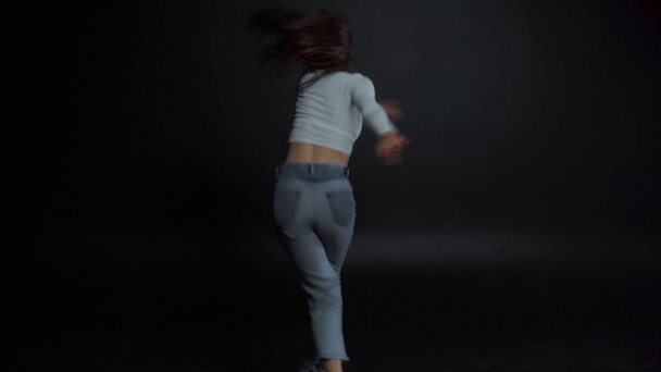 rack focus of woman dancing and jumping on black  - Filmati, video