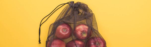 top view of red apples in eco friendly black mesh bag isolated on yellow, panoramic shot - Фото, зображення