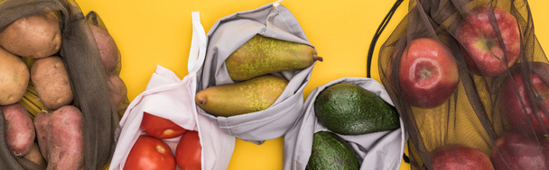 vista superior de manzanas maduras, peras, tomates, aguacate y papas en bolsas ecológicas aisladas en amarillo, plano panorámico
 - Foto, imagen