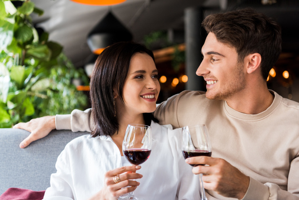 happy man and cheerful woman holding glasses with red wine  - Foto, afbeelding