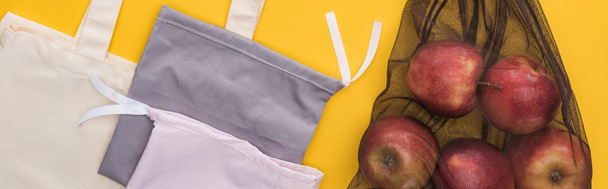top view of apples and eco friendly cotton bags isolated on yellow, panoramic shot - Φωτογραφία, εικόνα