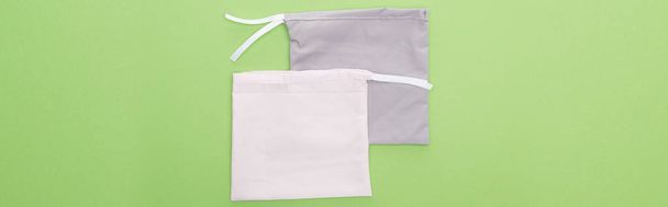 top view of eco friendly grey and white bags isolated on green, panoramic shot - Foto, immagini