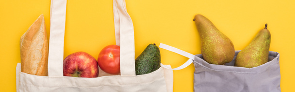 top view of ripe fruits, vegetables and baguette in eco friendly bags isolated on yellow, panoramic shot - Photo, Image