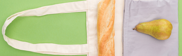 top view of pear and baguette on eco friendly bags isolated on green, panoramic shot - Fotoğraf, Görsel
