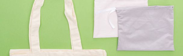 vista superior de bolsas ecológicas de algodón vacías aisladas en verde, plano panorámico
 - Foto, imagen