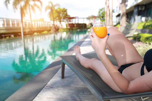 portrait of beautiful and sexy woman enjoy holiday vacation with orange juice in swimming pool - Photo, Image