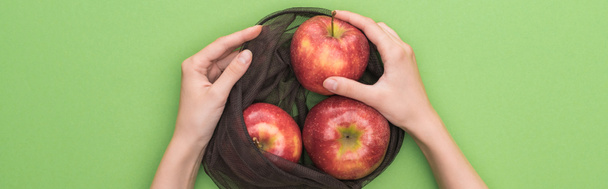 partial view of woman holding red ripe apples in eco friendly bag isolated on green, panoramic shot - Foto, Imagem