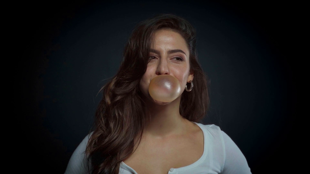happy girl blowing bubble gum on black  - Footage, Video