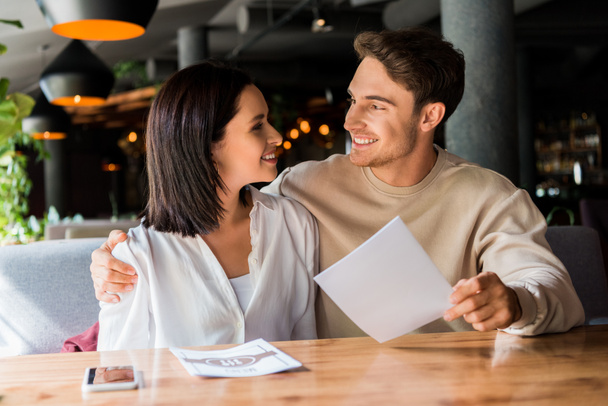 selective focus of happy man and woman smiling in restaurant  - Foto, Imagen