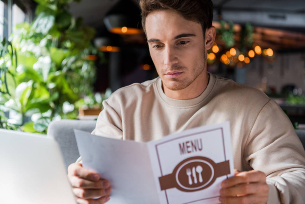 selective focus of handsome man holding menu in restaurant  - Foto, Bild