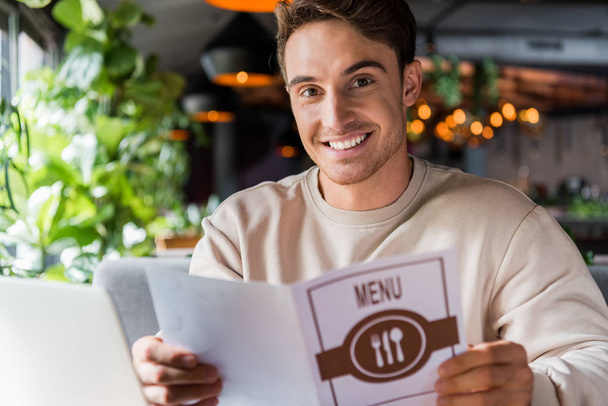 selective focus of positive man holding menu in restaurant  - Photo, Image