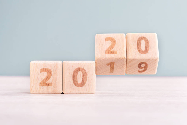 Abstract 2020 & 2019 New year countdown design concept - wood blocks cubes on wooden table and low saturation green background, close up, copy space. - 写真・画像