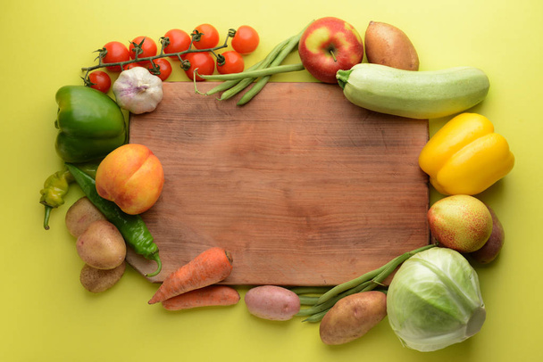 Board with many healthy vegetables and fruits on color background - Photo, Image