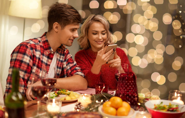 couple with smartphone at home christmas dinner - Photo, Image