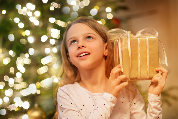smiling girl with christmas gift at home - Foto, Imagen