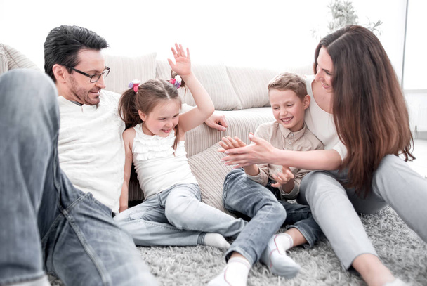 parents play with children sitting on the carpet in the living room - Photo, Image