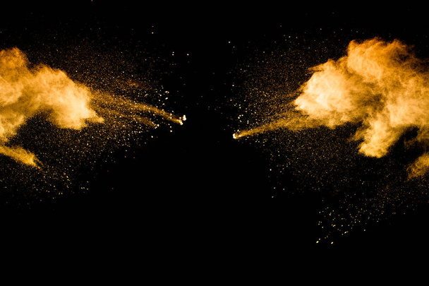 Abstract explosion of orange dust on black background. Freeze motion of orange powder splashing. - Photo, Image