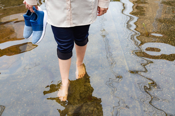 Žena kráčí po povodňové cestě s podkovy po silných deštích, příčinou svědění kůže patří, pozor na leptospirózu, to může být infikován kontaktem s vodou, sportovci nohy nebo tinea pedis - Fotografie, Obrázek
