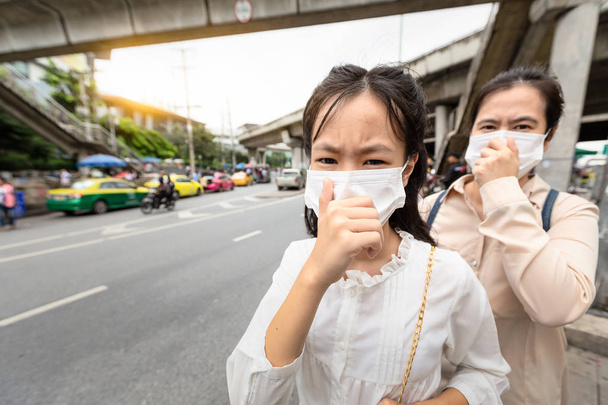 Madre e figlia asiatica bambina che indossa protezione maschera viso, le persone di sesso femminile impediscono la contaminazione dell'aria che entra nel corpo, malattie contagiose, dispersione dell'aria, inquinamento atmosferico, concetto di allergie alla polvere
 - Foto, immagini