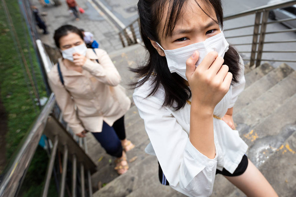 Asyalı kız çocuk ve annenin günlük rutini, her gün şehirde zehirli gaz solumak, günlük yaşama dönüşmek, yüz maskesi takan insanların hava kirliliği konsepti, toz alerjisi... - Fotoğraf, Görsel