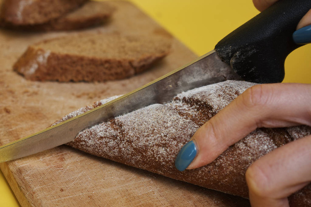 cropped shot of woman slicing fresh tasty rye bread - Foto, Bild