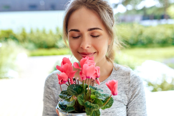 young woman with cyclamen flowers at summer garden - Foto, imagen