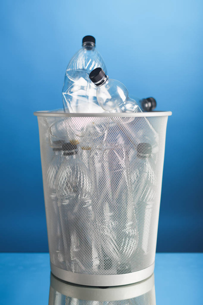 Mülleimer mit Plastikflaschen, blauer Hintergrund - Foto, Bild