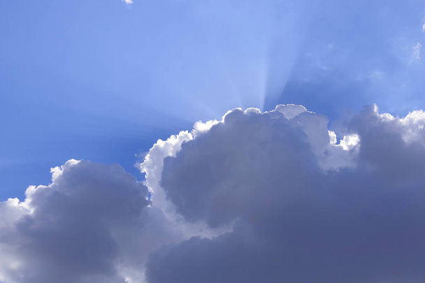 Οι ακτίνες του ήλιου που προέρχονται από τα σκούρα μπλε σύννεφα στο β - Φωτογραφία, εικόνα