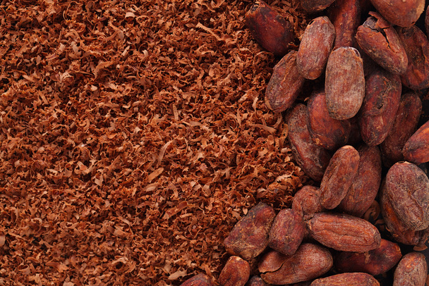 cacaobonen en geraspte chocolade achtergrond - Foto, afbeelding